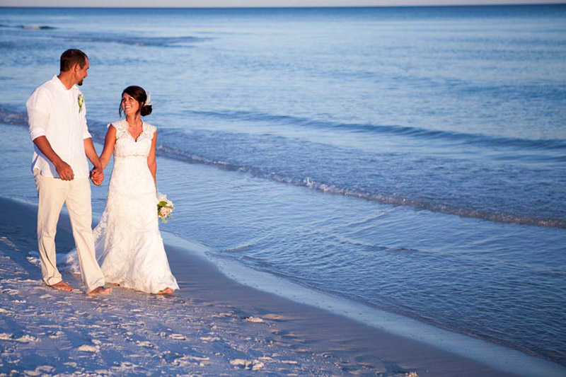 bride and groom walk along beach